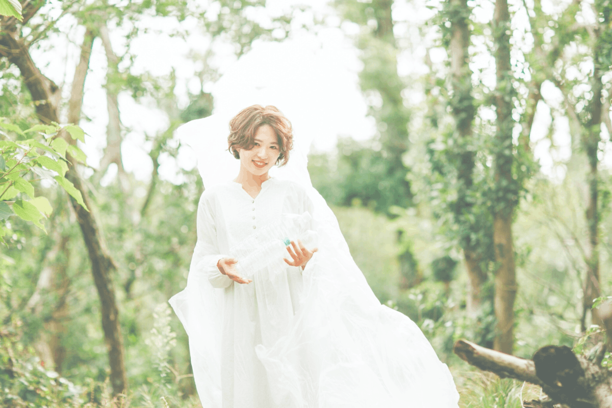 白いワンピースの女性と森